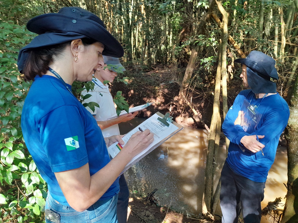 Empregados com pranchetas analisam condição do rio