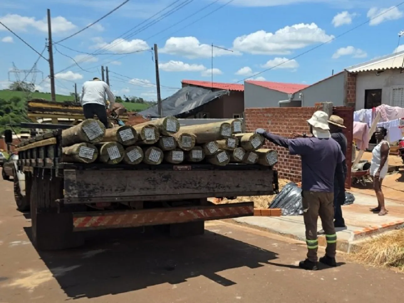 Caminhão com tubulação e dois homens ao lado 