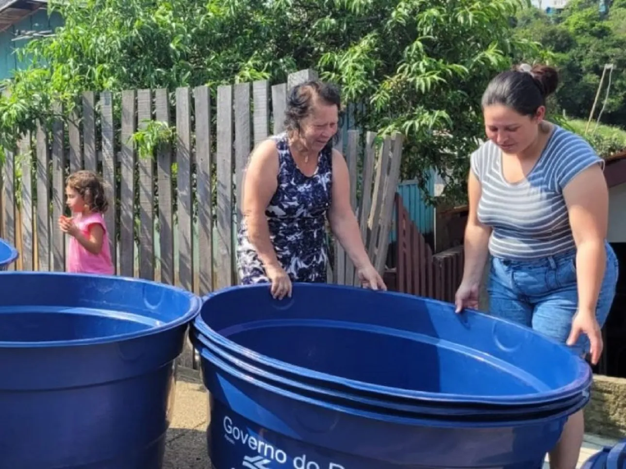 Duas mulheres segurando uma caixa d'água vazia