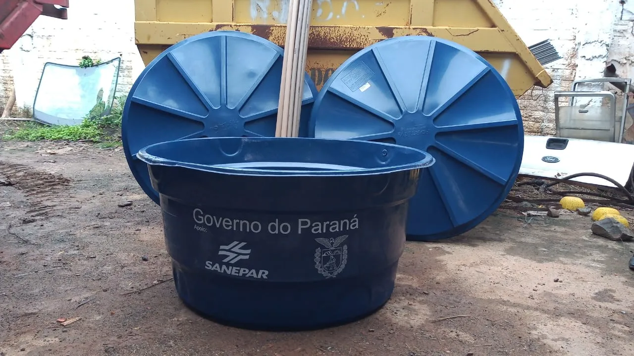 Caixa d'água azul em meio a um terreno 