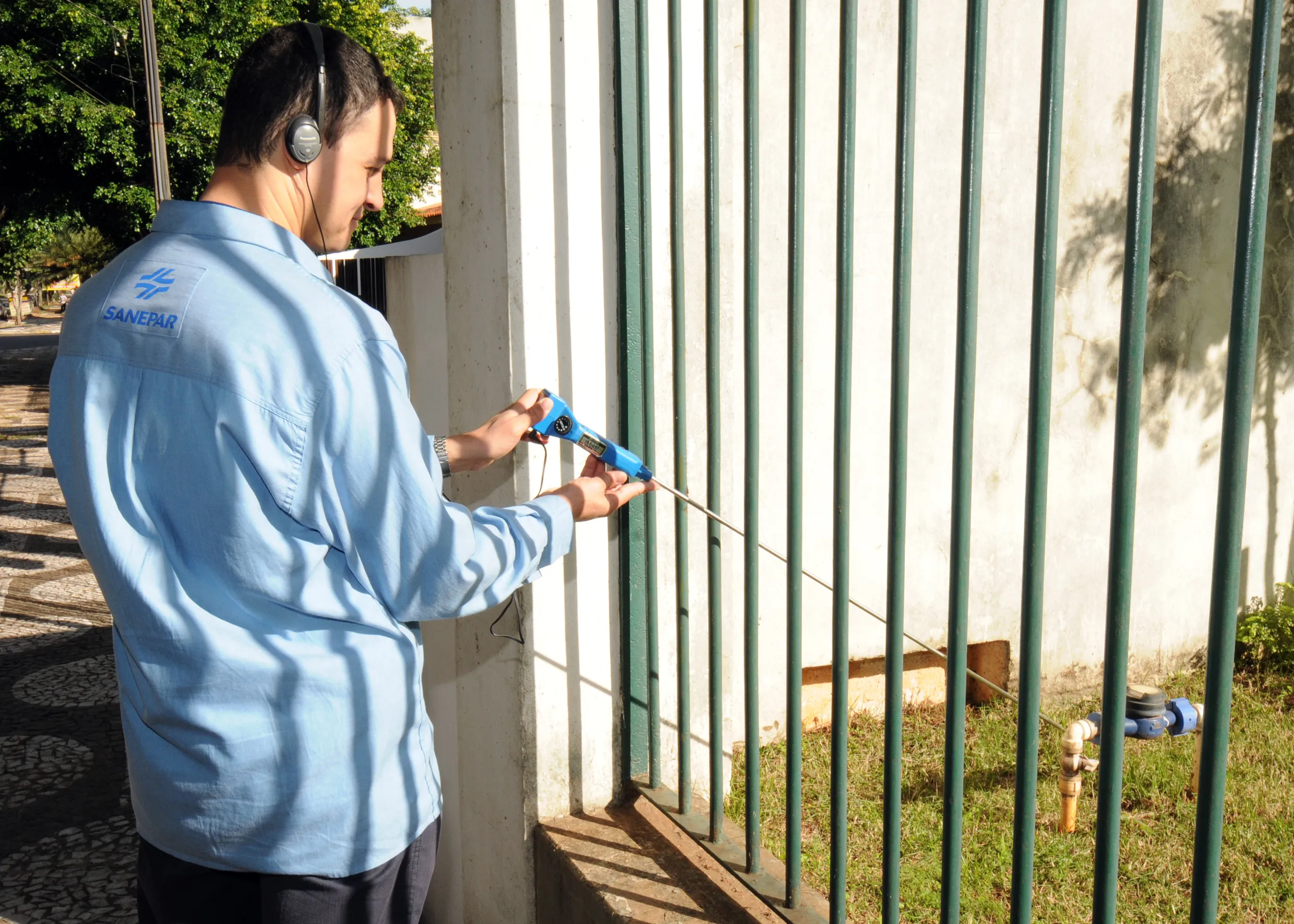 Homem com escuta no ouvido próximo segurando haste próxima à hidrômetro