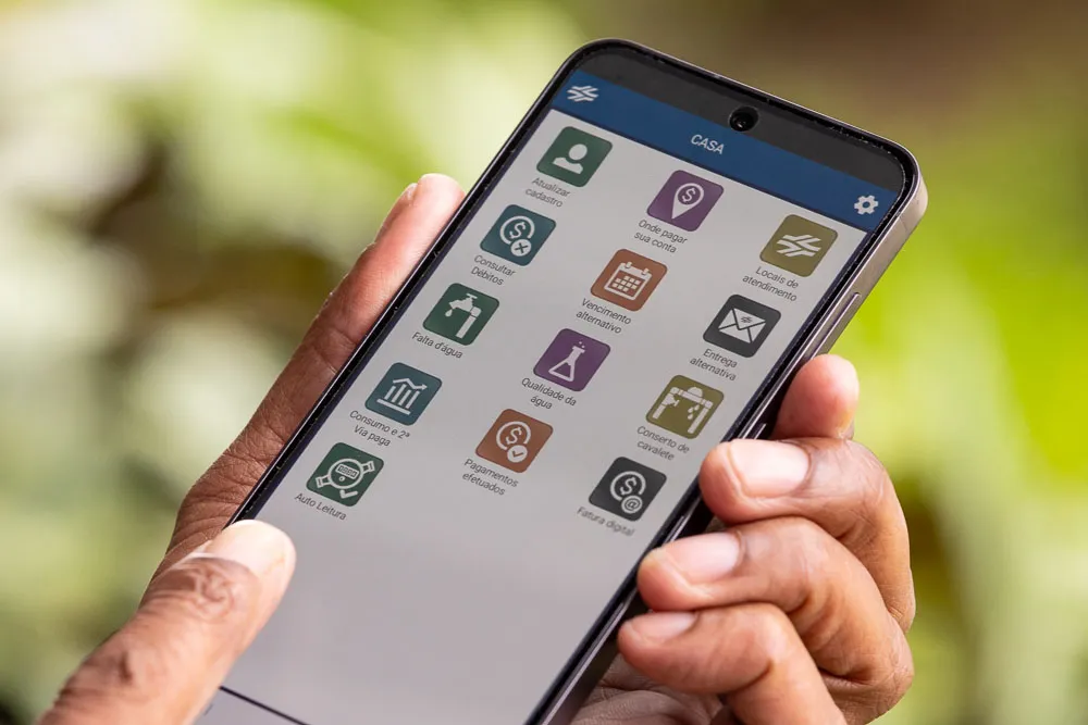 Mão segurando celular acessando aplicativo sanepar